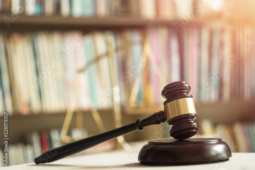 Wooden judge gavel with scales on library background