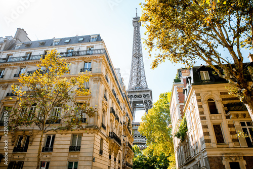 Piękny widok na ulicę ze starymi budynkami mieszkalnymi i wieżą Eiffla w świetle dziennym w Paryżu