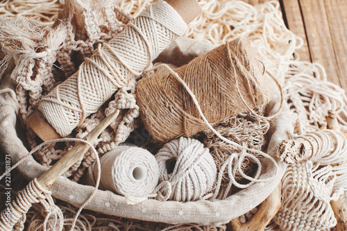 Needlework, macrame, knitting. Yarn and thread of natural colors in a wicker basket. Women's hobby.