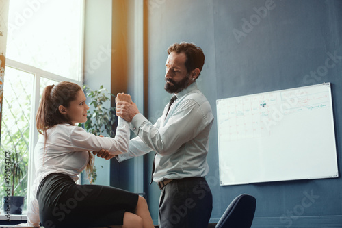 Man and woman doing armwrestling in office. Compete in business. Fight of genders concept.