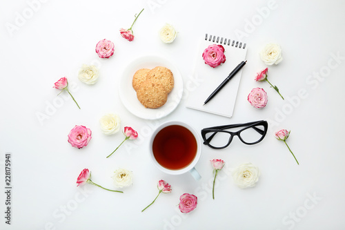Rose flowers with cup of tea and cookies on white background