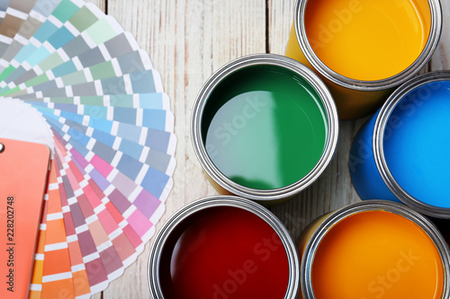 Cans with paint and color palette on wooden background, top view