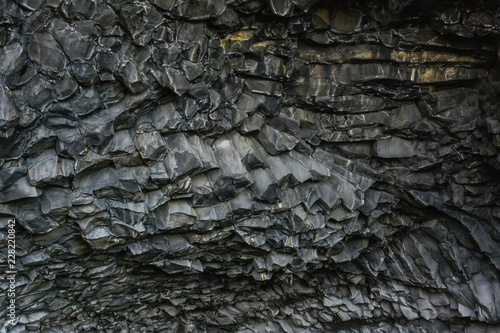 Basalt stone columns close-up on Reynisfjara black beach near Vik town, Iceland. Texture and background.