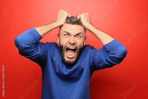 Portrait of aggressive man on color background