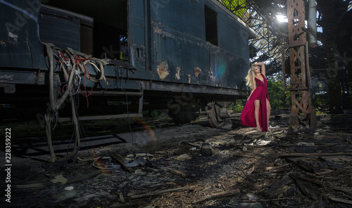 Beautiful woman on abandoned train station in red dress