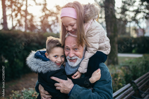 Happy grandfather having fun with his grandchildren in city park.