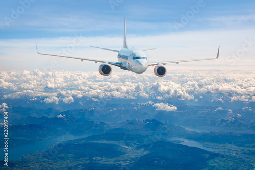 An airplane is flying over low clouds with blue sky - Airplane taking off from the airport - Travel by air transport