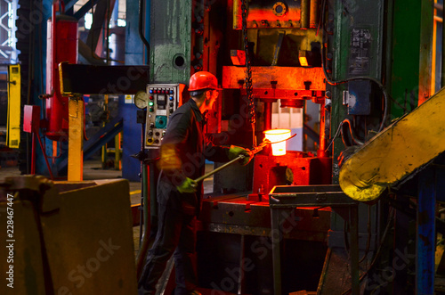 Hot iron in smeltery held by a worker. High precision hot forging product, automotive part production by hot forging process, automatice line hot forging. iron melting recycling work.