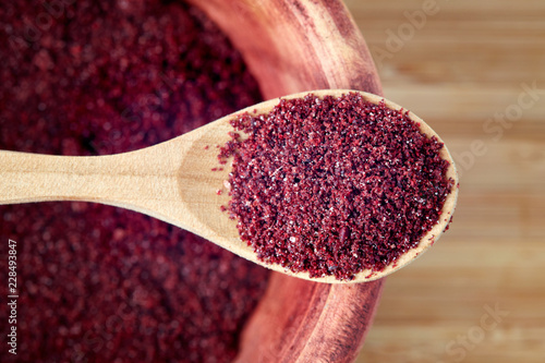 Close up of ground sumac spice powder in wooden spoon