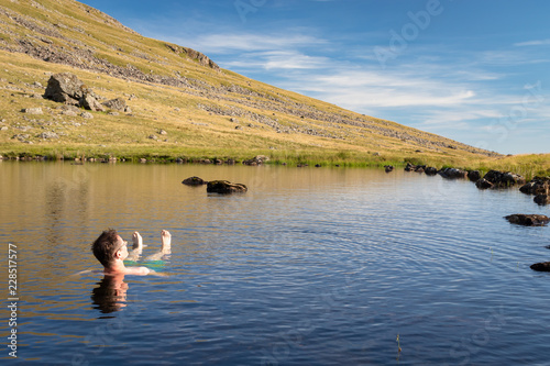 Man relaxing and enjoying refreshing bath in cold tarn water Lake District National Park, UK