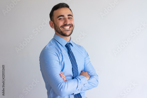 Portrait of joyful professional. Young business man blue shirt and tie crossing arms and smiling at camera. Successful businessman concept