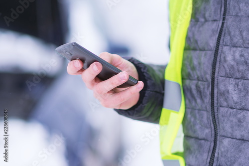 Man holding mobile phone and calling winter car services to help.