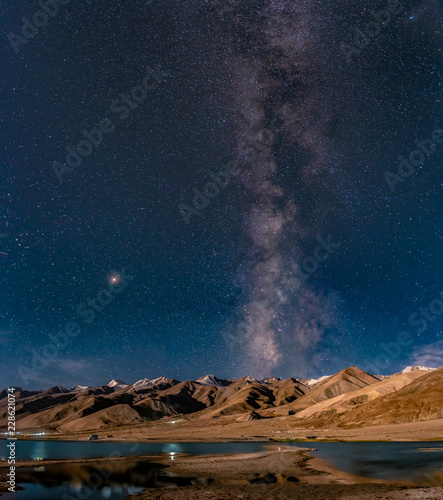 Panorama of arching Milky Way galactic center over the mountain at Pangong Lake or Pangong Tso, Ladakh, Jammu and Kashmir, India.