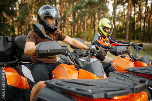 Two quad bike riders in helmets closeup, side view