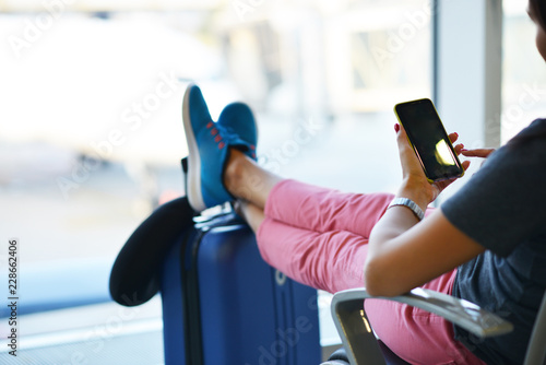Beautiful woman waiting for delayed or connection flight with luggage in airport 