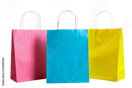 Many blank paper shopping bags of different colors, pink, blue and yellow isolated on white background. Blank colorful packets. Black friday sale concept. Close up copy space.