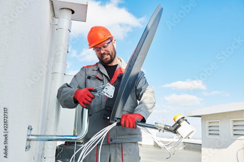 Service worker installing and fitting satellite antenna dish for cable TV