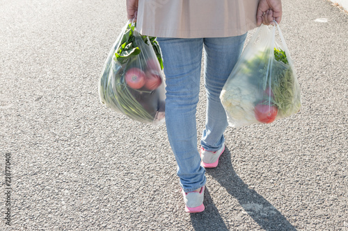 Woman holding a plastic bag of vegetables