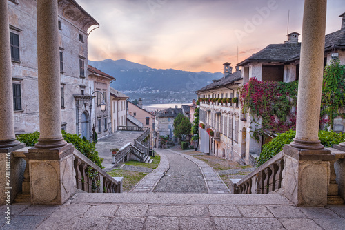 Beautiful scenic alley with historic and traditional houses and cobbled street at sunset. Picturesque Italian village, Orta San Giulio (street Albertoletti), on lake Orta, north Italy