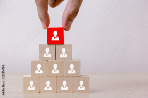 Hand putting wood cube block on top pyramid,human resource management and recruitment business concept, Business Strategy to success.