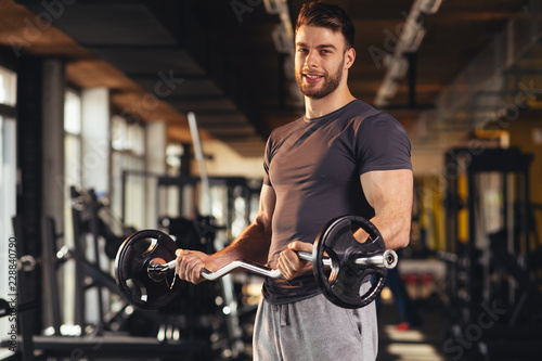 Handsome man doing biceps lifting in a gym