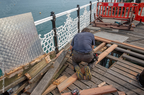 Brighton Sussex. Coast. England United Kingdom. Pier. Man repairing the wooden deck. Carpenter.