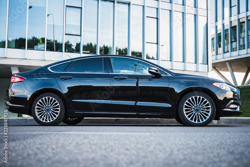 Luxurious black sedan in front of modern building