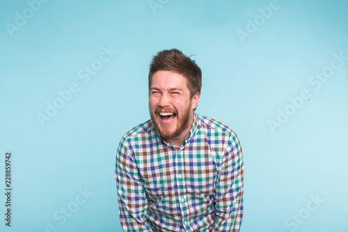 Emotion, people and fun concept - Young handsome man laughing on blue background