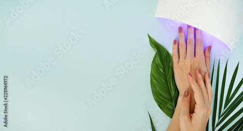 beautiful female manicured hands andled lamp on blue table