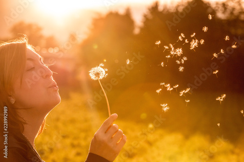 Junges Mädchen bläst Samen einer Pusteblume, Sonnenuntergang im Herbst mit Textfreiraum