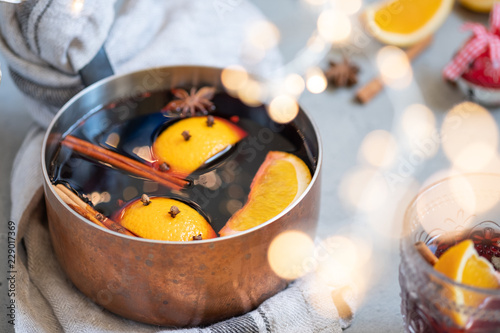 Mulled wine hot drink with oranges and spices in copper pot