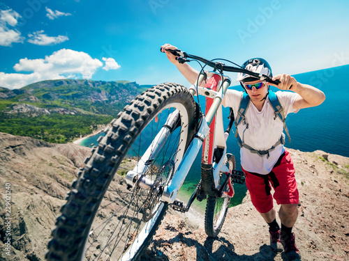Man pushing a mountain bike up the hill. Adventure travel on bicycle.