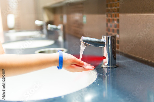 Boys are washing their hands, sensors in the automatic faucet in the mall.