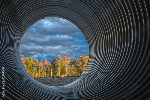 view of sunset woods through large culvert