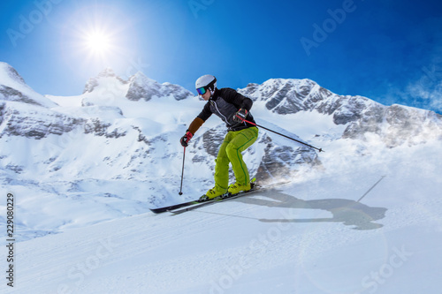 Skier skiing downhill during sunny day in high mountains in Dachstein area, Austria.