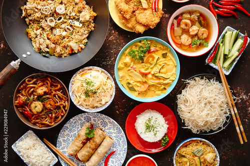 Asian oriental food composition in colorful dishware, served on dark rustic background, top view. Chinese, vietnamese, thai cuisine set. With copy space.