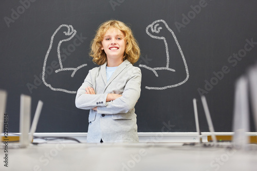 Starker Junge in Schule mit Muskeln an Tafel