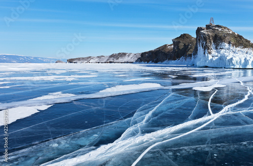 Baikal Lake in February sunny cold day. Blue smooth ice with cracks near the Cape Horin-Irgi (Kobylia Golova) of Olkhon Island. Beautiful winter landscape