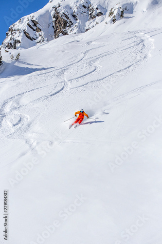 freeride skier skiing downhill, facing forward, white snowy background