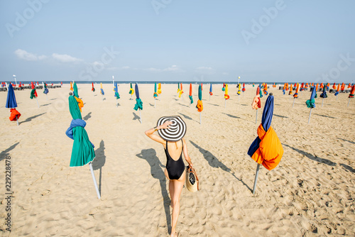 Woman walking on the beach with colorful umbrellas in Deauville, famous french resort in Normandy