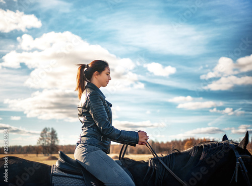 Russian Girl rides a black horse on a Sunny day