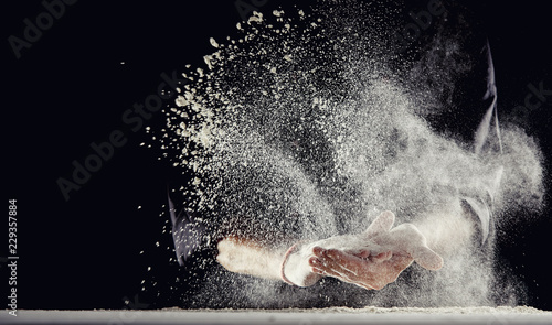 Flour spraying into air while man wipes his hands
