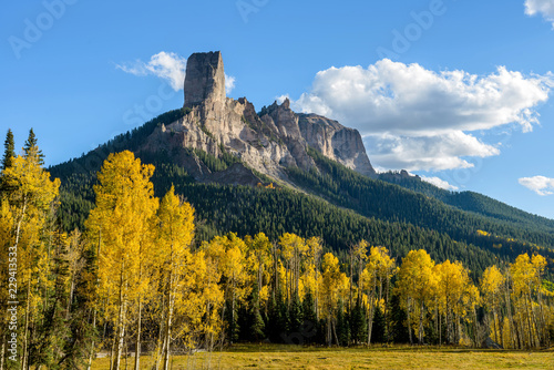 Chimney Peak - Evening view of Chimney Peak rock formations, 11,781 ft (3,591 m), surrounded by golden autumn aspen trees, near the summit of Owl Creek Pass, 10,114 ft (3,083m). Colorado, USA.