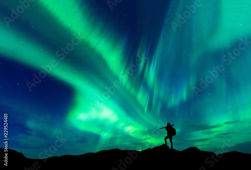 Aurora borealis with silhouette standing photographer on the mountain.Freedom traveller journey concept