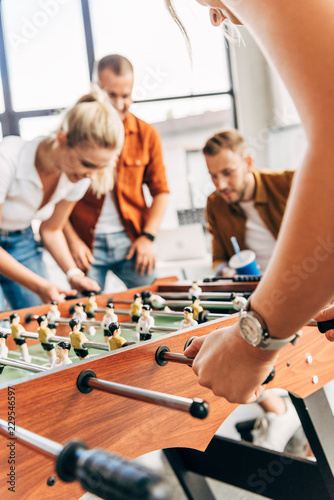 cropped shot of young casual business people playing table football at office and having fun together