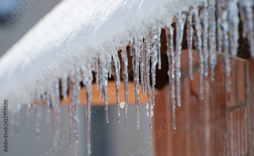 Icicles hang on a house roof / Eiszapfen hängen an einem Hausdach