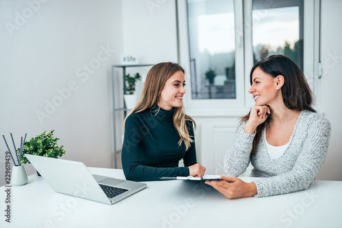 Two smiling female colleagues in the office. Working together.