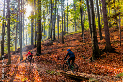 Kolarstwo, para rowerzystów górskich na szlaku rowerowym w lesie jesienią. Kolarstwo górskie w jesień krajobraz lasu. Mężczyzna i kobieta na rowerze MTB płyną pod górę szlaku.