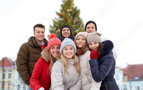 holidays, friendship and people concept - happy friends over christmas tree at tallinn old town hall square background