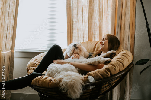 Girl holding her dog on comfy chair